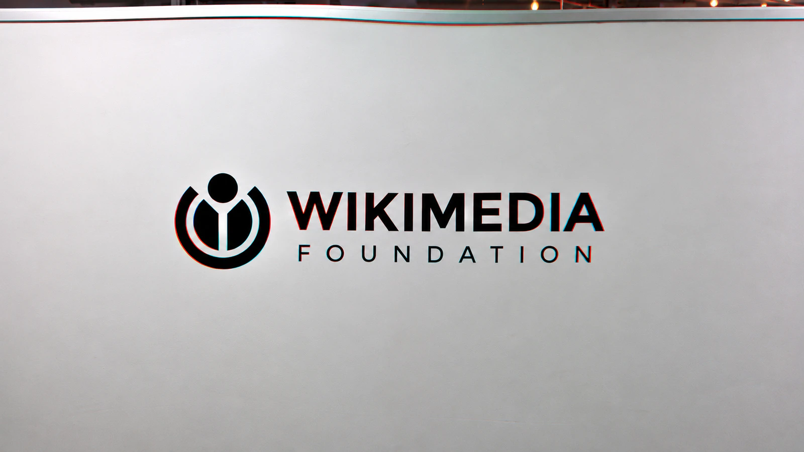 Foto d’archivio: Gregory Varnum / Wikimedia Foundation, CC BY-SA 4.0 (https://creativecommons.org/licenses/by-sa/4.0/). Insegna della sede, 2018. Ritaglio e trattamento RGB/onda con AI: KANSEI, stessa licenza.